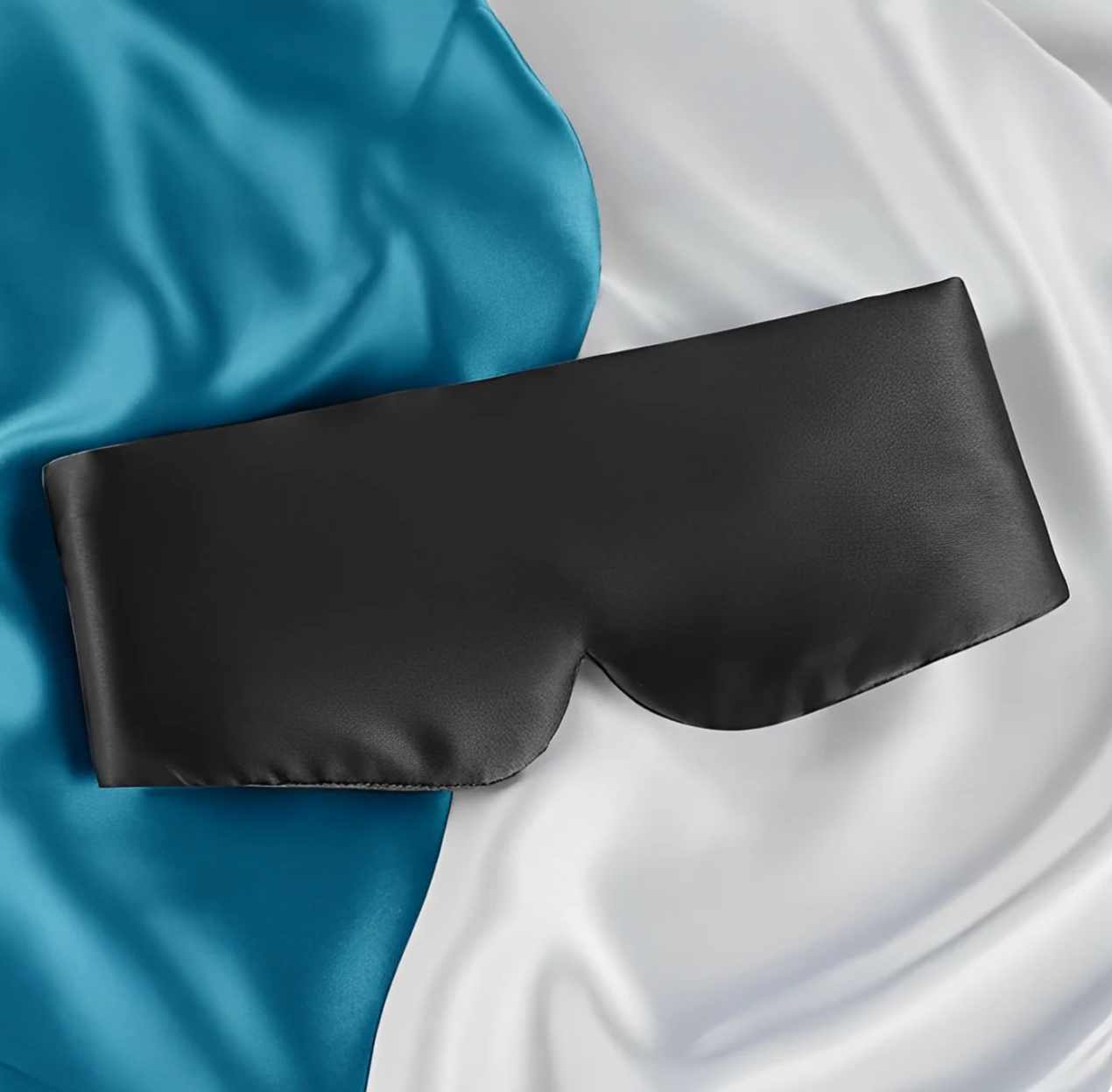 Black satin eye mask on a blue and white fabric background